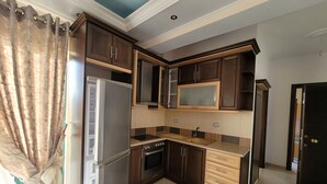 A modern kitchen with dark wooden cabinets, a stainless steel refrigerator, a microwave, and a double sink. - Remarkable 4-Bed House in Ksamil for families (Ksamil)