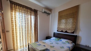 A neatly arranged bedroom with a bed, a bedside table, a nightstand, and a window with curtains. - Remarkable 4-Bed House in Ksamil for families (Ksamil)