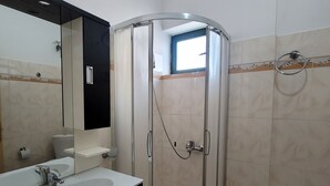 A bathroom with a glass-enclosed shower, a sink with a mirror, and a toilet. - Remarkable 4-Bed House in Ksamil for families (Ksamil)