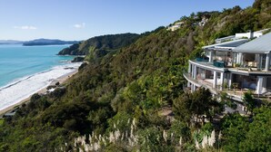 A coastal property with a large house featuring multiple balconies overlooking the beach and ocean.