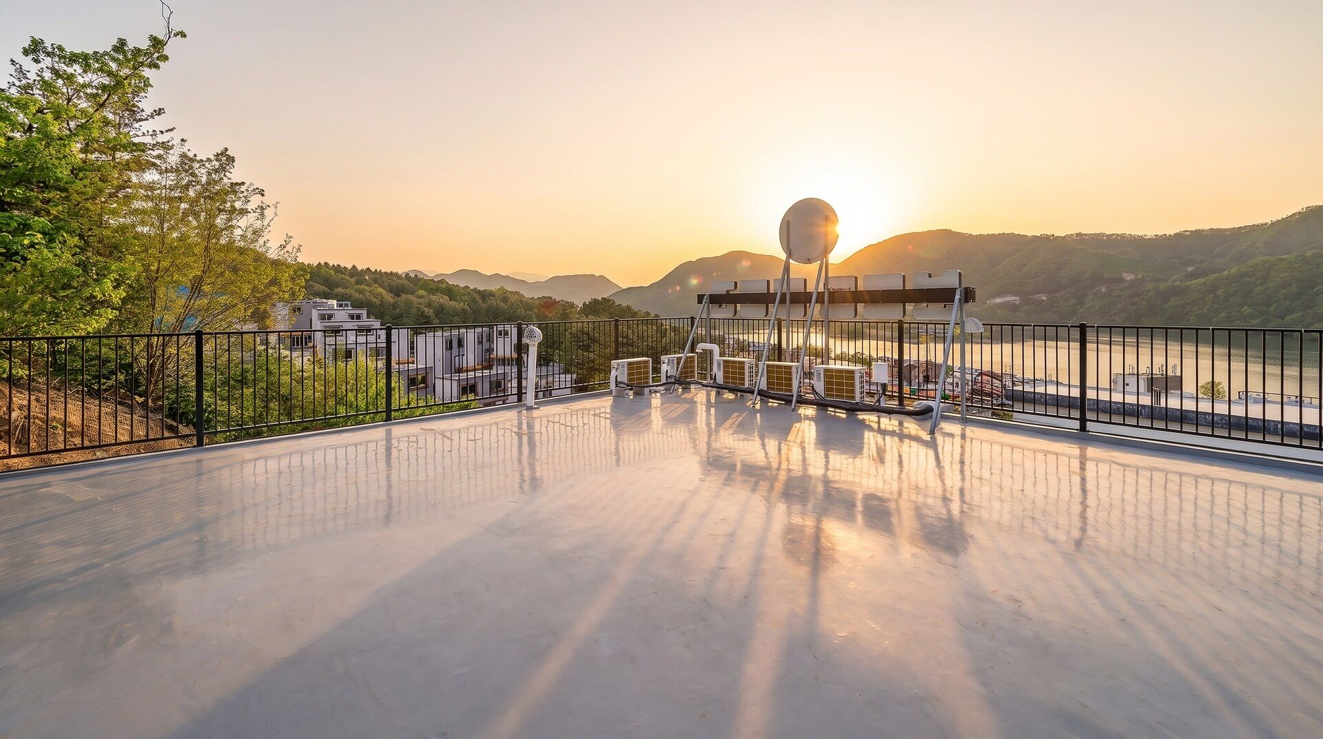 A rooftop terrace with a view of the sunset, a pool, and a mountain landscape.