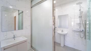 Un baño moderno con cabina de ducha de vidrio, un lavamanos y un espejo.