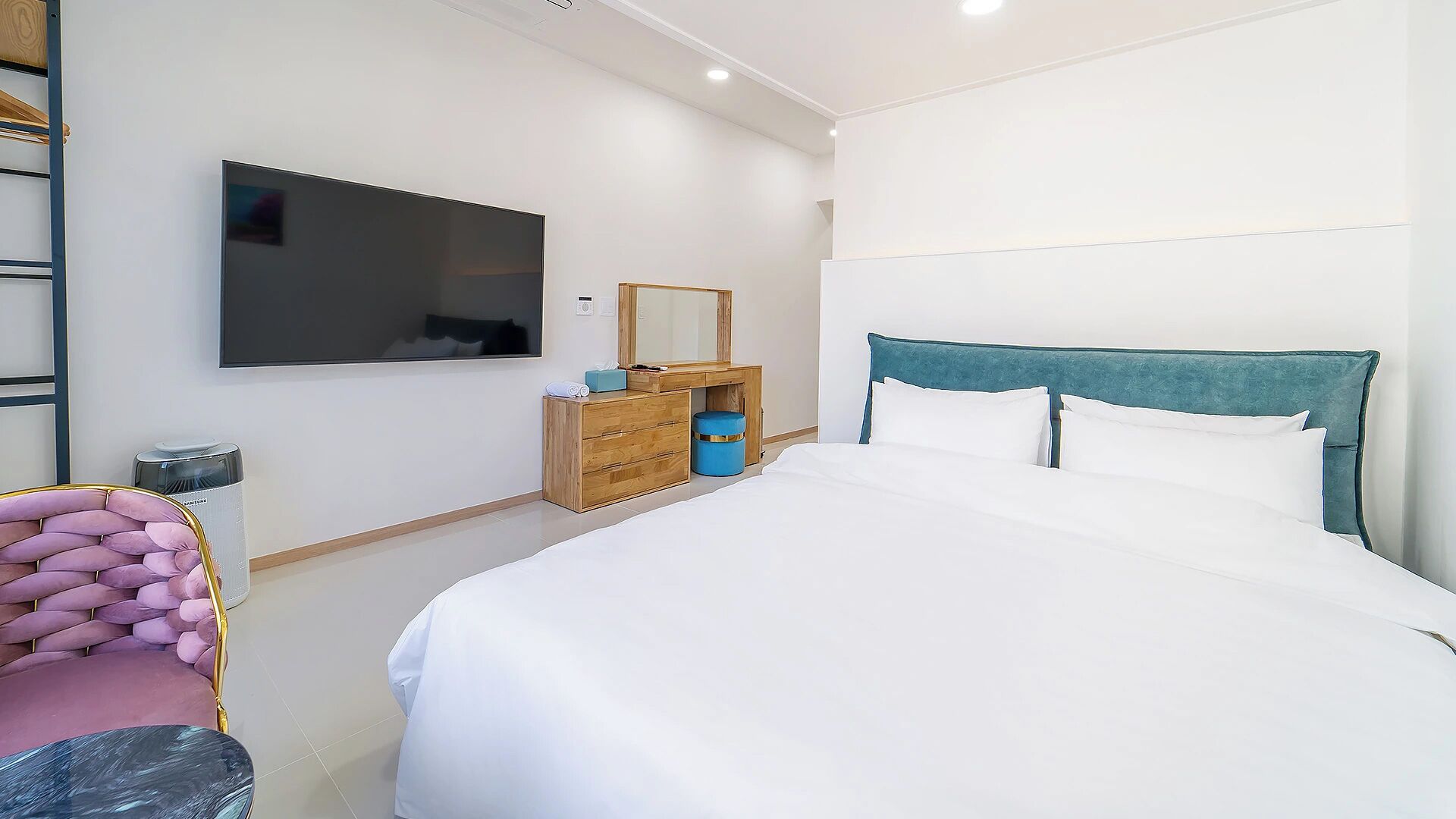 Una habitación de hotel con una cama, un tocador, un espejo, un televisor y una silla.