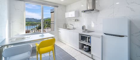 Una cocina moderna con vista a un lago, un comedor con una silla amarilla y un horno empotrado.