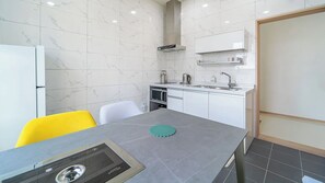 Cocina compacta con microondas, hervidor y un mueble pequeño.