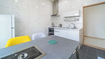 A compact kitchen with a microwave, kettle, and a small cabinet.