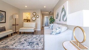 Una sala de estar con sofá, sillón y un tapete estampado.