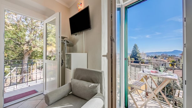 En balkon med tv, sofa og et bord med stole.