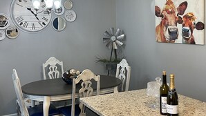Un coin repas comprenant une table ronde, des chaises, une horloge, des éléments de décoration murale et une éolienne.