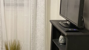 Un meuble noir pour télévision à écran plat, agrémenté d’un objet décoratif et d’une petite plante.