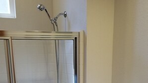 Kylpyhuoneessa on lasiseinällä varustettu suihku, valkoinen wc-istuin ja allas, jossa on pesuallas.