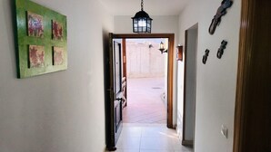 A hallway with a tiled floor, a green wall with artwork, a black lantern hanging from the ceiling, and a door leading to an outdoor area. - Incredible duplex in La Lajita (La Lajita)