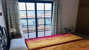 A room with a bed, a window with a view of the sea, and a small table with a lamp. - Incredible duplex in La Lajita (La Lajita)