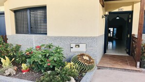 A building entrance with a tiled patio, a mailbox, and a variety of potted plants. - Incredible duplex in La Lajita (La Lajita)