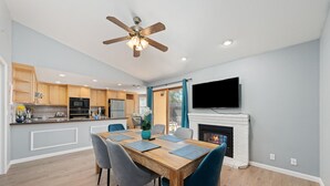 A modern kitchen with wooden cabinets, a built-in microwave, and a dining area with a wooden table and blue chairs. - Gorgeous House with POOL!! (Elk Grove)