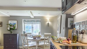 Une cuisine avec une table à manger, des chaises, un buffet et une fenêtre.