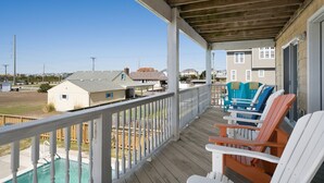 Une véranda abritée avec une piscine, une terrasse en bois et un espace salon extérieur.