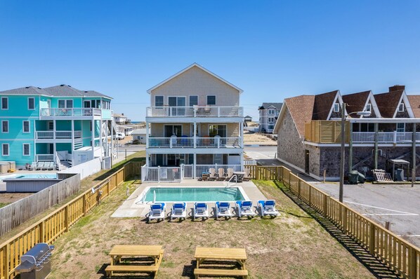 A two-story building with a swimming pool and lounge chairs in front.
