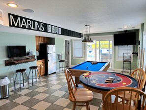 A room with a pool table, pool cues, and a television. - Turning Tide: Semi-Oceanfront, private pool & hot tub, rec room with pool table! (Nags Head)