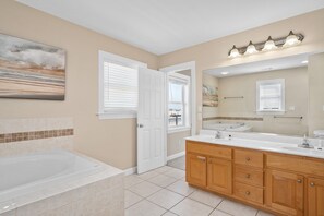 Une salle de bain avec une baignoire, un meuble-lavabo et un grand miroir.