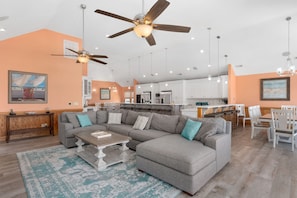 A spacious living room with a sectional sofa, a coffee table, and a ceiling fan.