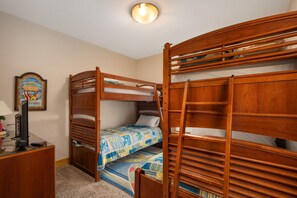 A room with bunk beds, a desk with a computer, and a framed picture on the wall. - Turtle's Nest: Oceanfront, pool, hot tub, theater & rec rooms and elevator! (Kill Devil Hills)