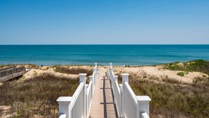 A wooden boardwalk leading to the beach with white railings and a clear view of the ocean. - Turtle's Nest: Oceanfront, pool, hot tub, theater & rec rooms and elevator! (Kill Devil Hills)
