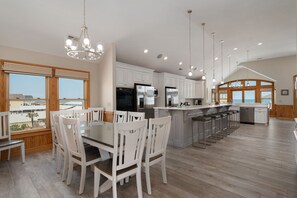 A modern kitchen with white cabinets, stainless steel appliances, and a large island with bar stools.