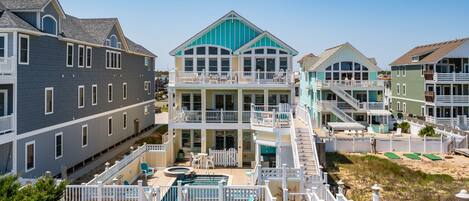 A beachfront property with multiple buildings, a swimming pool, and a fenced deck area.