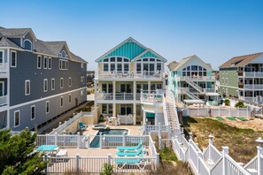 A multi-story beachfront property with a swimming pool, multiple balconies, and a beach access area. - Turtle's Nest: Oceanfront, pool, hot tub, theater & rec rooms and elevator! (Kill Devil Hills)