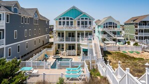 A multi-story beachfront property with a swimming pool, multiple balconies, and a beach access area. - Turtle's Nest: Oceanfront, pool, hot tub, theater & rec rooms and elevator! (Kill Devil Hills)