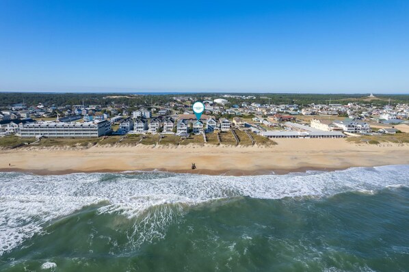 An aerial view of a coastal town with a beach, buildings, and a lighthouse. - Turtle's Nest: Oceanfront, pool, hot tub, theater & rec rooms and elevator! (Kill Devil Hills)