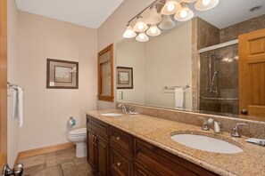 A bathroom with two sinks, a large mirror, and a shower. - Turtle's Nest: Oceanfront, pool, hot tub, theater & rec rooms and elevator! (Kill Devil Hills)