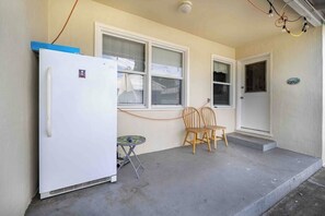 A compact living space with a white refrigerator, two windows, a door, and a small table with chairs.