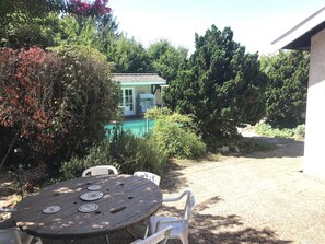 Een terras met een ronde tafel en stoelen, een zwembadje en een huis op de achtergrond.