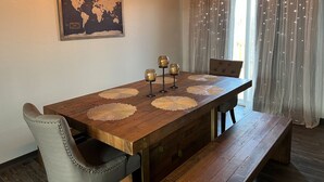 A dining area with a wooden table, four chairs, and a world map on the wall. - Luxury Stay w/Coffee Bar & Movie Room, 2 King Suites, Firepit — Black Hills View (Rapid City)