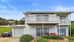 Une maison à deux étages avec un garage, un balcon et un jardin bien entretenu.
