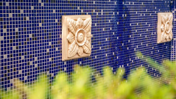 A wall with blue mosaic tiles and two square, beige decorative panels. - Watch House (Dongshan)