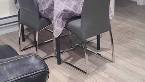 En matplats med ett bord dukat för fyra personer, omgiven av stolar, en krukväxt med blommor och en mikrovågsugn placerad ovanför bordet.