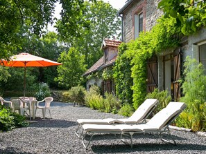 A patio with two lounge chairs, a table, and an umbrella.