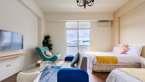 A modern hotel room with a large TV, a sofa, a bed, and a balcony with a city view. - Moon Deer (Taitung)