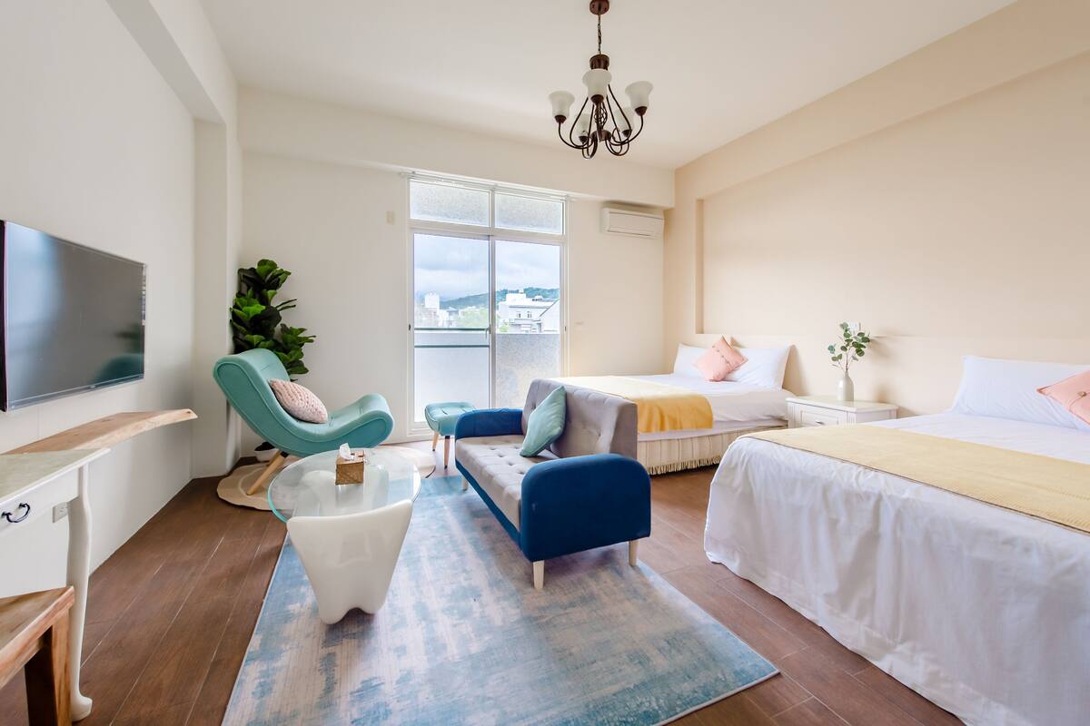 Una habitación de hotel moderna con una cama grande, un sofá, un televisor y un balcón con vistas.