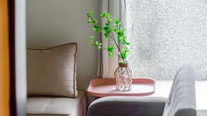 A modern living room with a beige sofa, a small side table with a vase of green plants, and a grey armchair. - Moon Deer (Taitung)