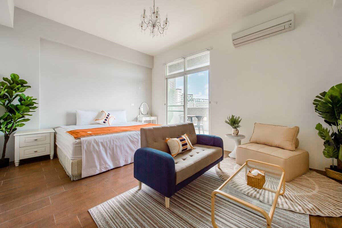 Un dormitorio moderno con cama, sofá, una mesita de centro y ventana con vistas.