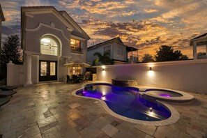 Relax by the pool in a serene outdoor setting, surrounded by a well-maintained patio area and a stone-tiled deck.