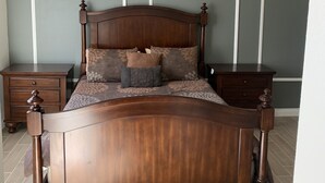 Une chambre à coucher avec un lit en bois, deux tables de chevet et un ventilateur de plafond.