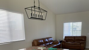 Un salon spacieux avec une table à manger en bois, des canapés en cuir et un luminaire suspendu.