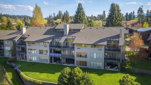 Un edificio residenziale moderno a più piani con balconi, ampie finestre e un prato ben curato.