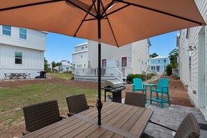 Un espace extérieur aménagé avec une table et des chaises, un barbecue et un parasol.