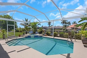 A pool area with a clear view of the surrounding landscape, including palm trees and houses.